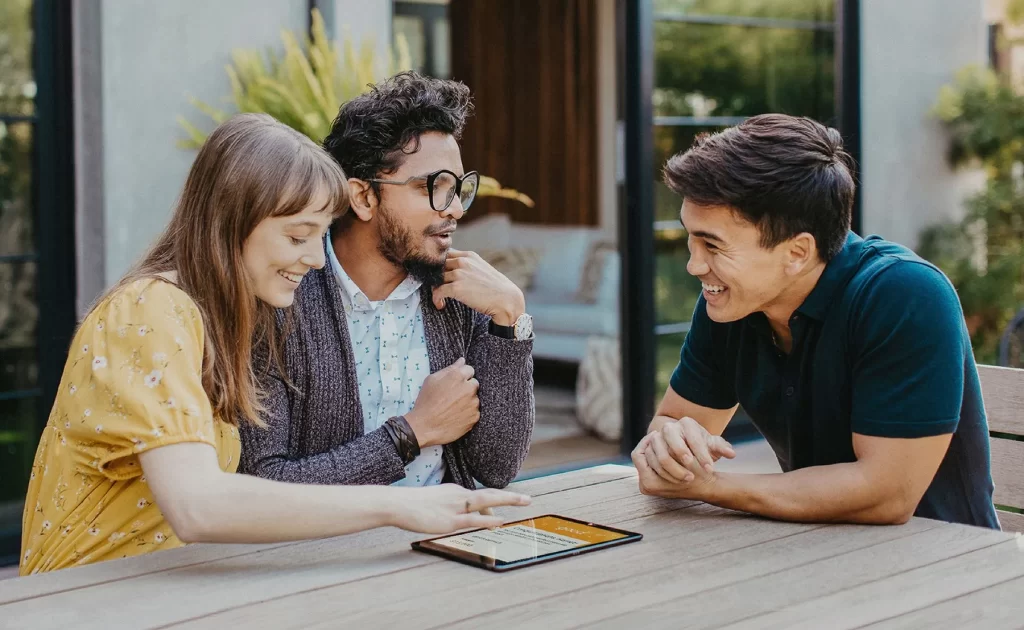 a trendy woman with her two male companions looking at HVAC options on a tablet